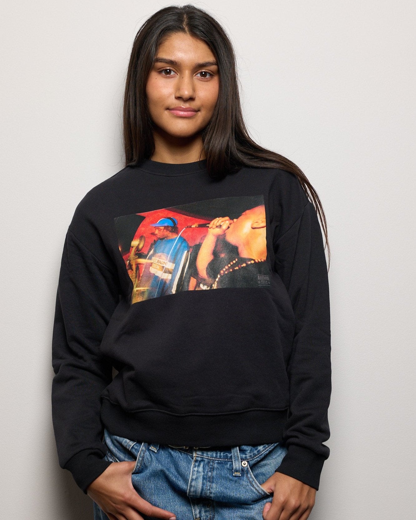 Model wearing Archive Tees women's sweatshirt in black with vintage photograph of DJ and MC at Movement Drum and Bass club night at Bar Rumba London in 1997. Vintage clubbing sweatshirt by Archive Tees. Sold by Archive Tees shop.